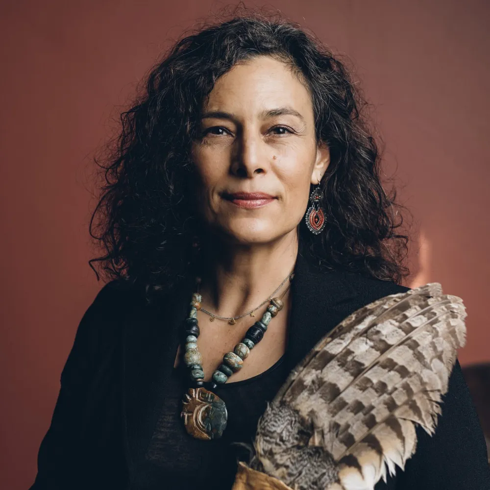 Annalouiza Armendariz holding a feather fan, photographed against a deep red backdrop.